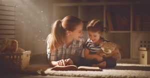 happy family mother and daughter read a book in the evening at home